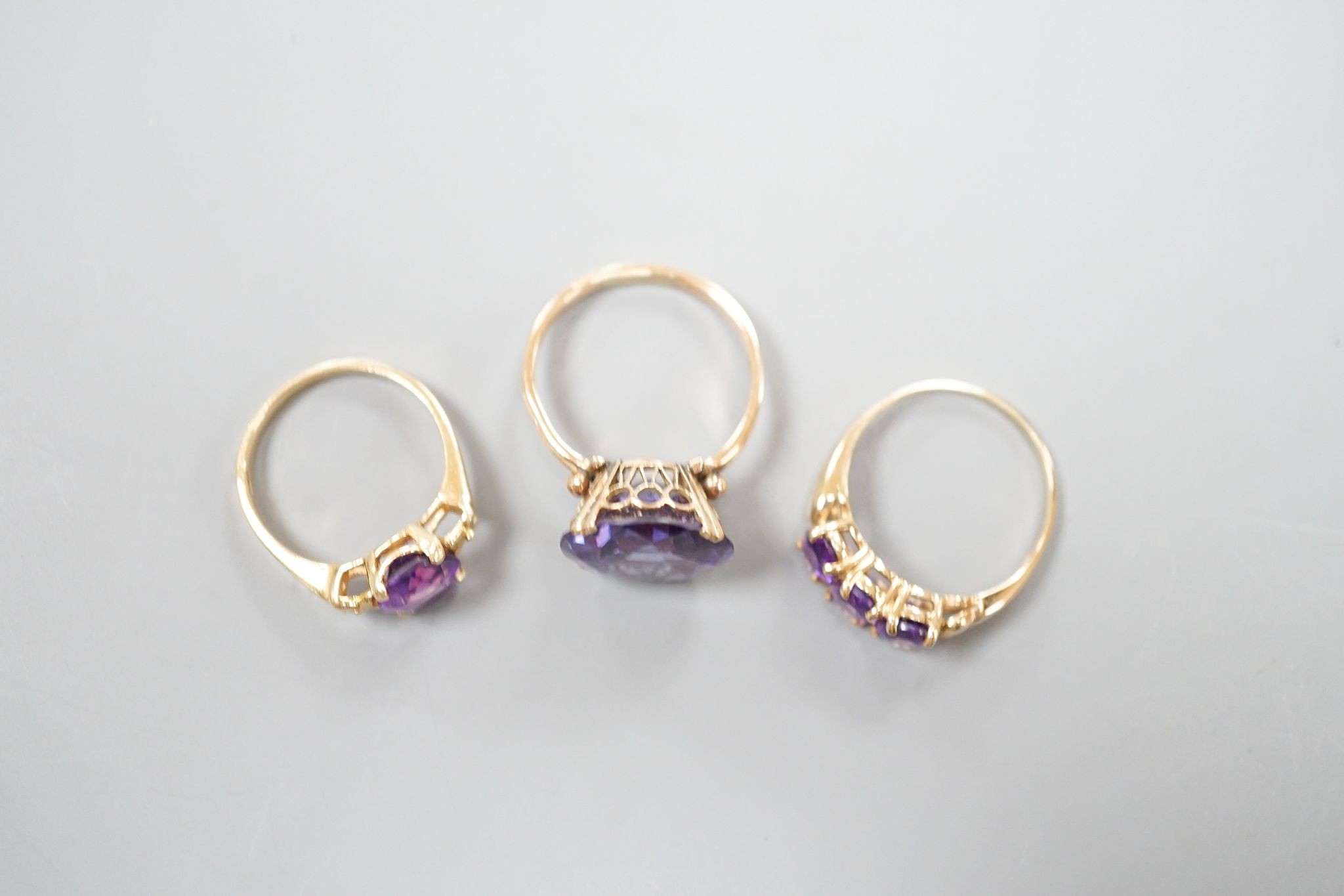 Two modern 14k yellow metal and gem set rings, including amethyst, size N, gross weight 7.4 grams and a similar 10k and three stone amethyst ring, size Q/R, gross 2.3 grams.